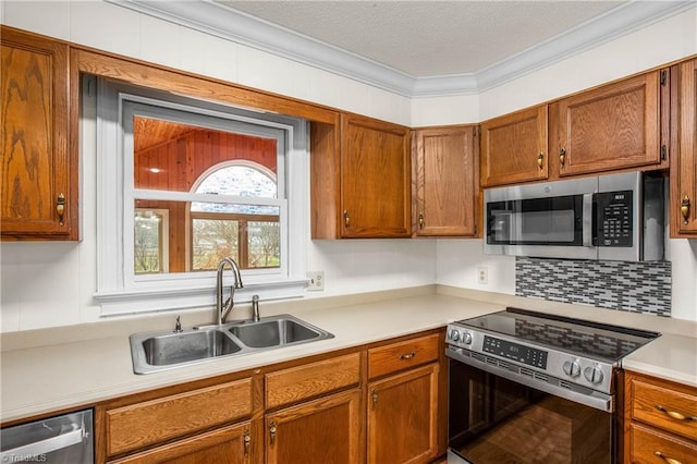 kitchen featuring ornamental molding, a sink, light countertops, appliances with stainless steel finishes, and brown cabinets