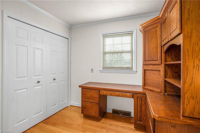 unfurnished office with a textured ceiling, built in study area, light wood-type flooring, and ornamental molding