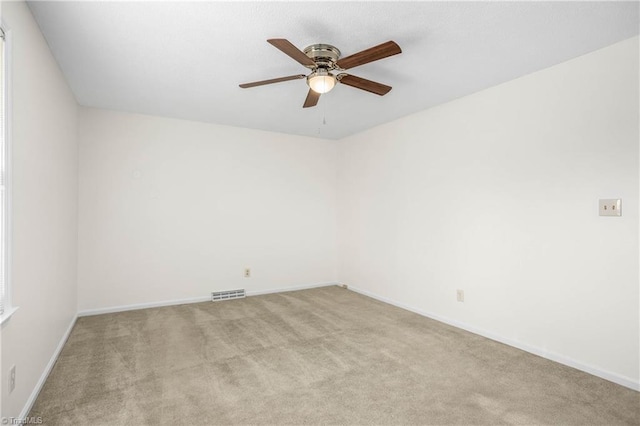 carpeted spare room featuring a ceiling fan, visible vents, and baseboards