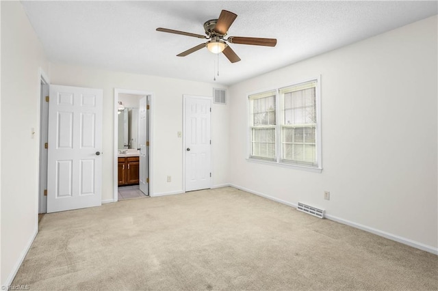 unfurnished bedroom with light carpet, visible vents, ensuite bathroom, and baseboards