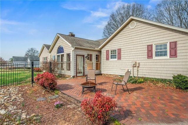 rear view of property with a patio, fence, a chimney, and a fire pit