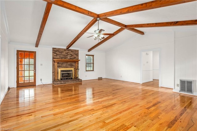 unfurnished living room with visible vents, a ceiling fan, a fireplace, light wood finished floors, and vaulted ceiling with beams