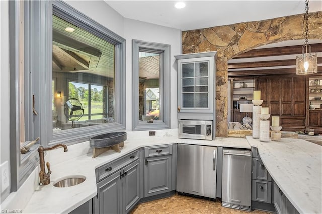 interior space with light stone countertops, hanging light fixtures, stainless steel appliances, beamed ceiling, and sink