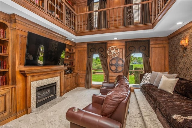 living room with a towering ceiling, built in features, and a premium fireplace