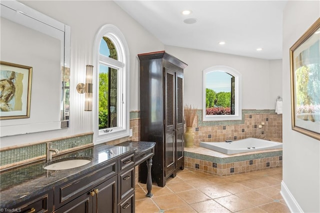 bathroom with tile floors, tiled tub, and vanity