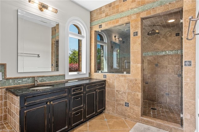 bathroom featuring tile walls, tasteful backsplash, tile floors, a shower with shower door, and vanity