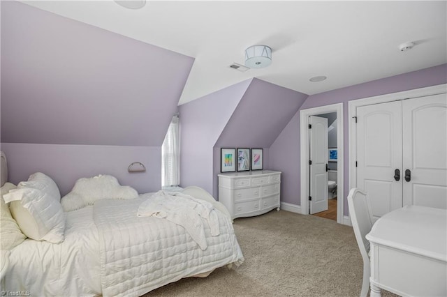 bedroom featuring light carpet, vaulted ceiling, and a closet