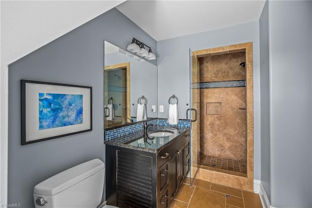 bathroom featuring tile flooring, vanity, toilet, and a tile shower