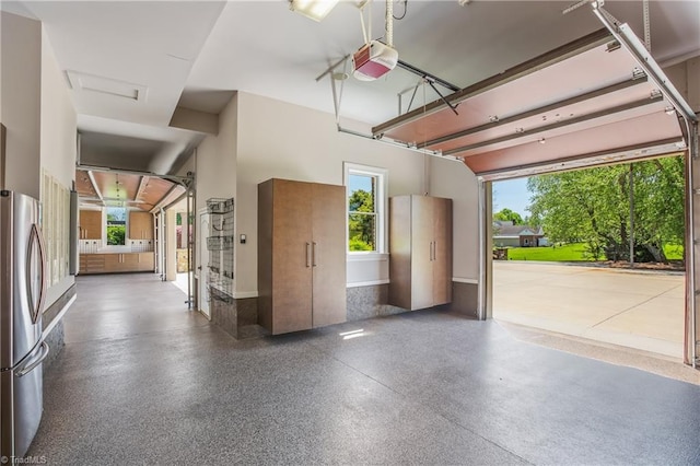 garage with a garage door opener and stainless steel refrigerator