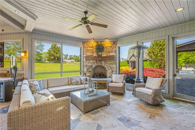 sunroom with ceiling fan and a fireplace