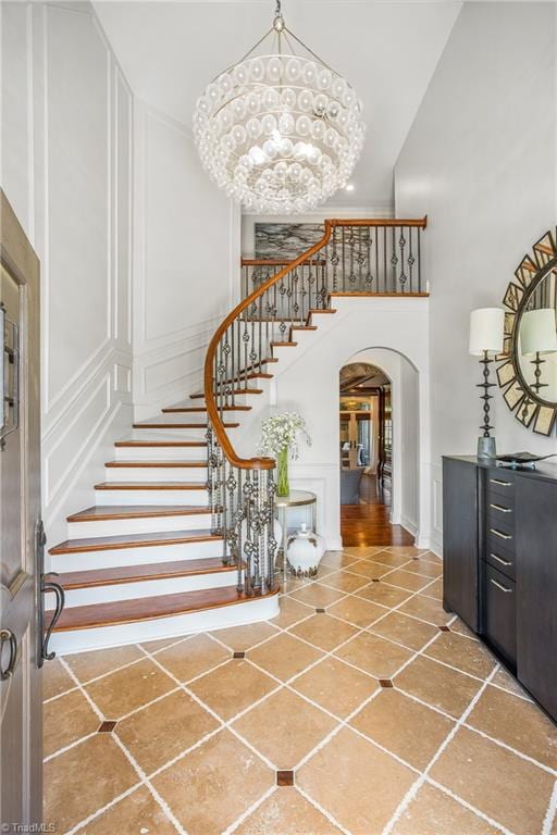 stairway with an inviting chandelier, tile floors, and a towering ceiling