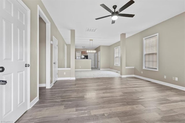 unfurnished living room featuring light hardwood / wood-style flooring and ceiling fan with notable chandelier