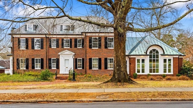 view of front facade featuring a standing seam roof, metal roof, and brick siding