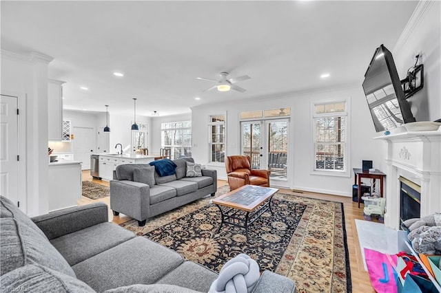 living room with ornamental molding, a high end fireplace, and light hardwood / wood-style floors