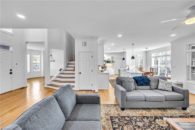 living room with ceiling fan, ornamental molding, sink, and light hardwood / wood-style floors