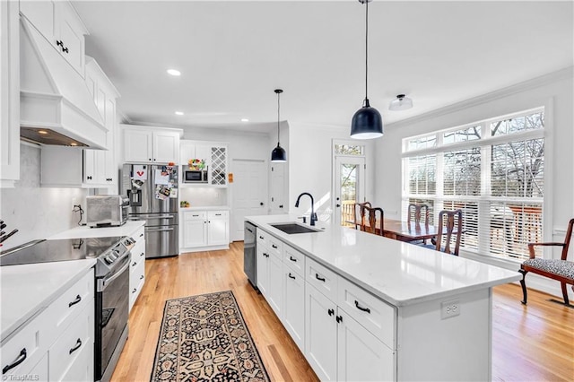 kitchen with white cabinetry, sink, an island with sink, and premium range hood