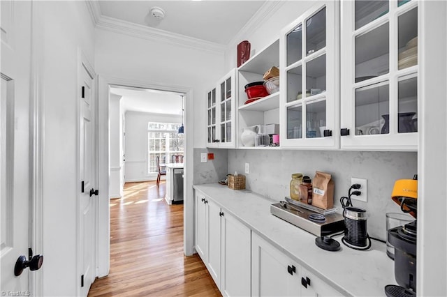 interior space with crown molding, light stone countertops, light hardwood / wood-style flooring, and white cabinets