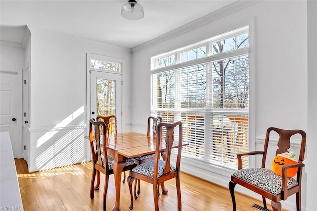 dining space featuring crown molding and light hardwood / wood-style flooring