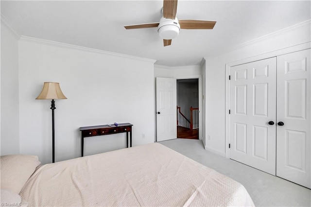 carpeted bedroom featuring crown molding, ceiling fan, and a closet