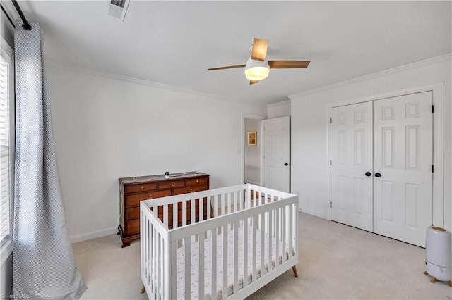 bedroom featuring crown molding, light colored carpet, ceiling fan, and a closet