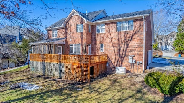 back of property featuring a wooden deck, a yard, and a sunroom