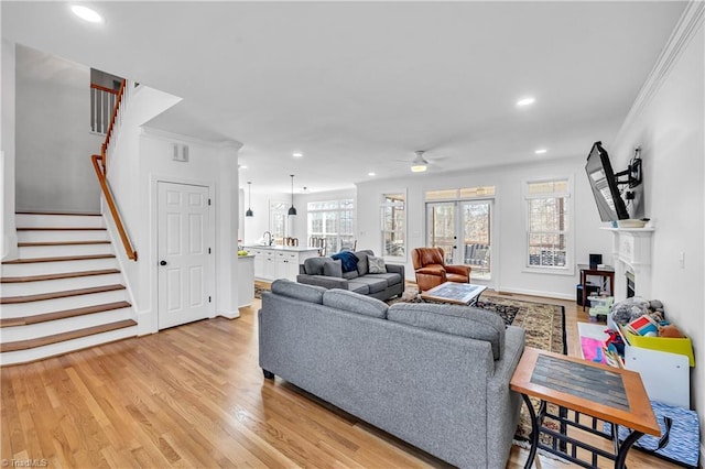 living room featuring crown molding, light hardwood / wood-style floors, and ceiling fan