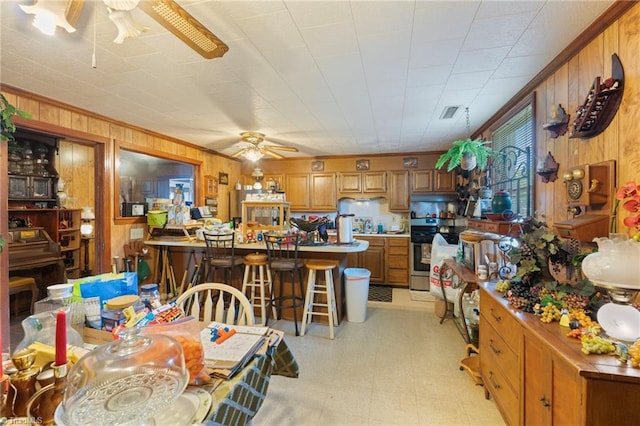 dining space featuring ceiling fan, wood walls, and crown molding