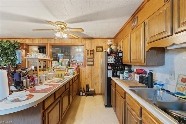 kitchen with crown molding, sink, and wooden walls