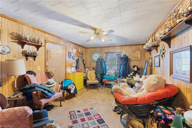 interior space with wooden walls, crown molding, carpet flooring, and ceiling fan