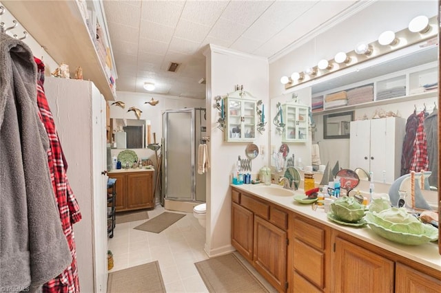 bathroom featuring a shower with door, toilet, tile patterned floors, vanity, and crown molding