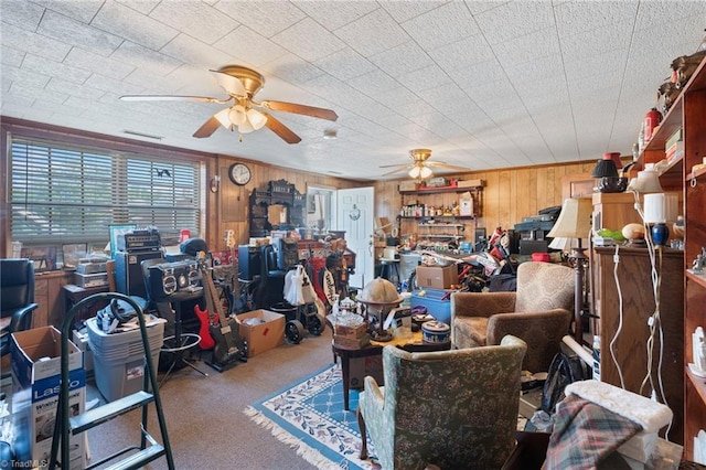 misc room featuring ceiling fan, wood walls, and carpet