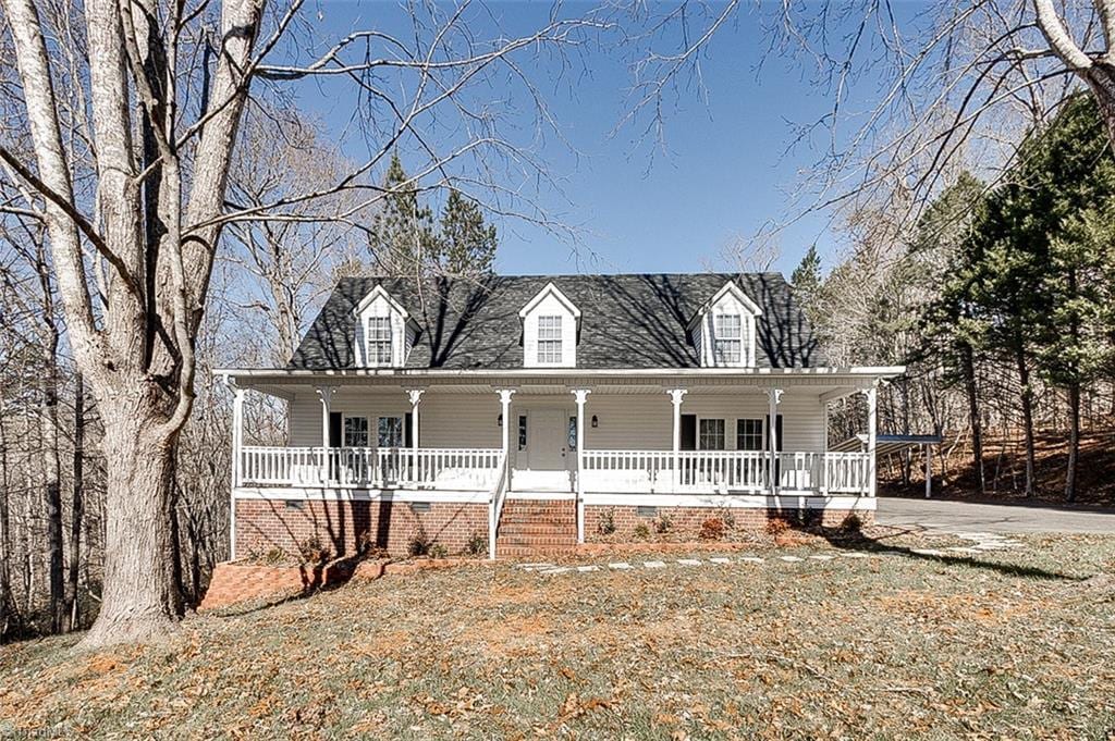 new england style home featuring covered porch and a front yard