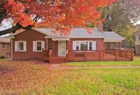 back of property with a wooden deck and a yard