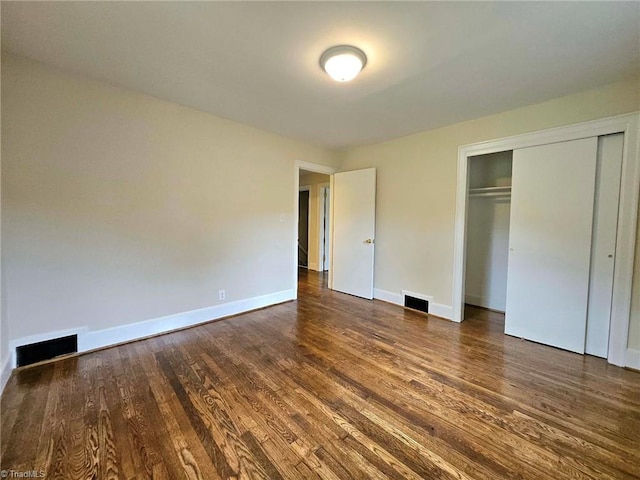 unfurnished bedroom featuring a closet and dark hardwood / wood-style flooring