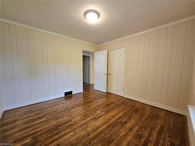 spare room featuring wood walls, crown molding, and dark hardwood / wood-style flooring