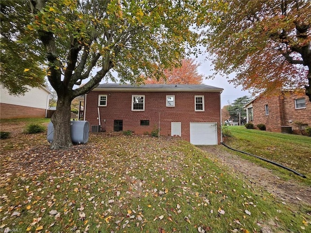 rear view of property featuring a yard, central AC, and a garage