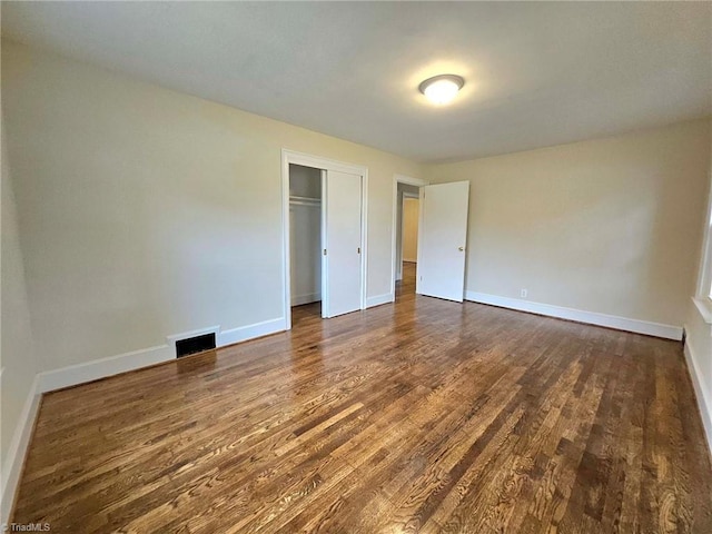 unfurnished bedroom featuring a closet and dark hardwood / wood-style flooring