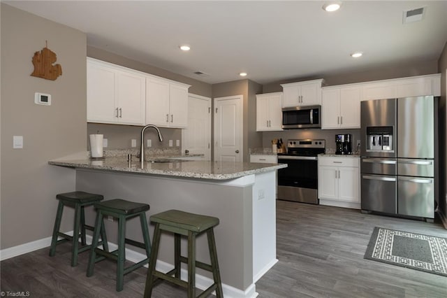 4628 Heatherly Rd, Winston-Salem, NC 27105 - kitchen featuring stainless steel appliances, dark wood finished floors, a peninsula, white cabinets, and recessed lighting