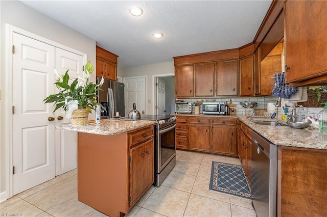 4680 Sherborne Dr, Pfafftown, NC 27040 - kitchen with stainless steel appliances, light tile patterned floors, a center island, brown cabinets, and recessed lighting