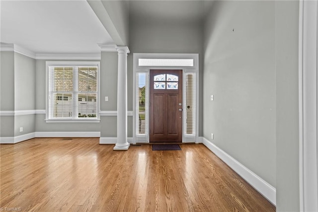 foyer with ornate columns, crown molding, and wood-type flooring