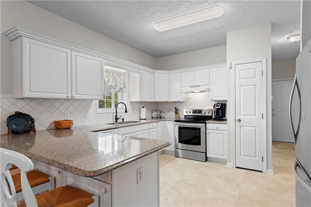 kitchen with sink, kitchen peninsula, a breakfast bar area, white cabinetry, and stainless steel appliances