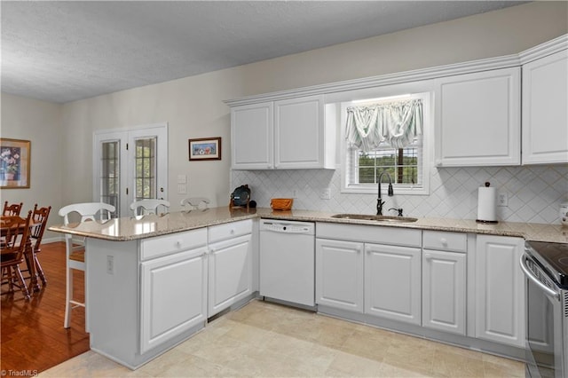 kitchen featuring kitchen peninsula, dishwasher, white cabinets, and sink