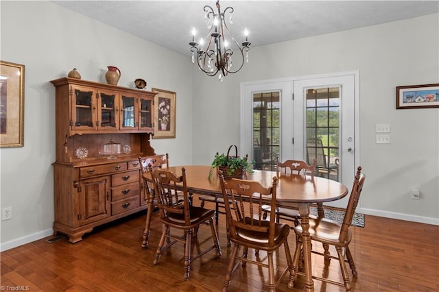 dining area featuring dark hardwood / wood-style floors, french doors, and an inviting chandelier