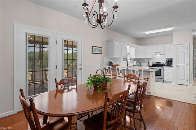 dining space featuring light hardwood / wood-style floors, a notable chandelier, and sink