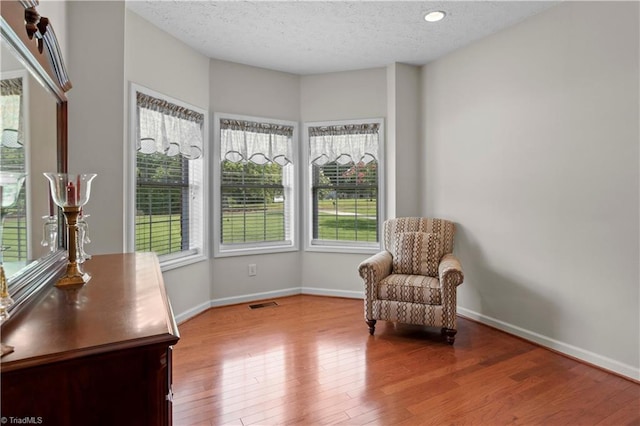 living area featuring a healthy amount of sunlight, a textured ceiling, and light hardwood / wood-style floors