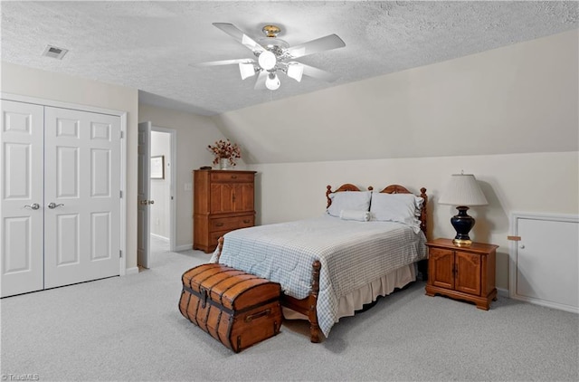 carpeted bedroom featuring a textured ceiling, a closet, lofted ceiling, and ceiling fan