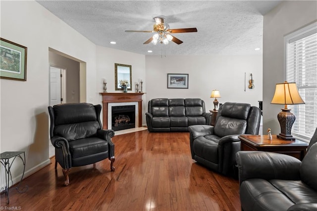 living room with ceiling fan, hardwood / wood-style floors, and a textured ceiling