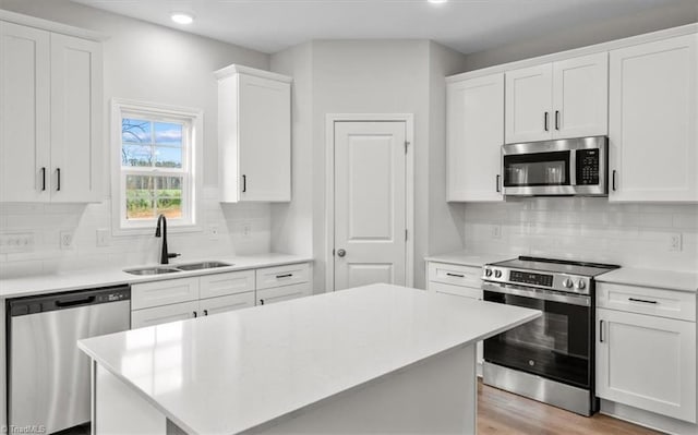 kitchen with sink, stainless steel appliances, white cabinetry, and backsplash