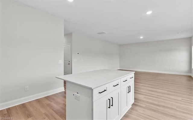 kitchen featuring white cabinets, light hardwood / wood-style flooring, and a center island