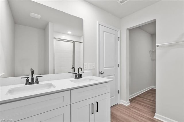 bathroom with a shower with door, hardwood / wood-style floors, and vanity